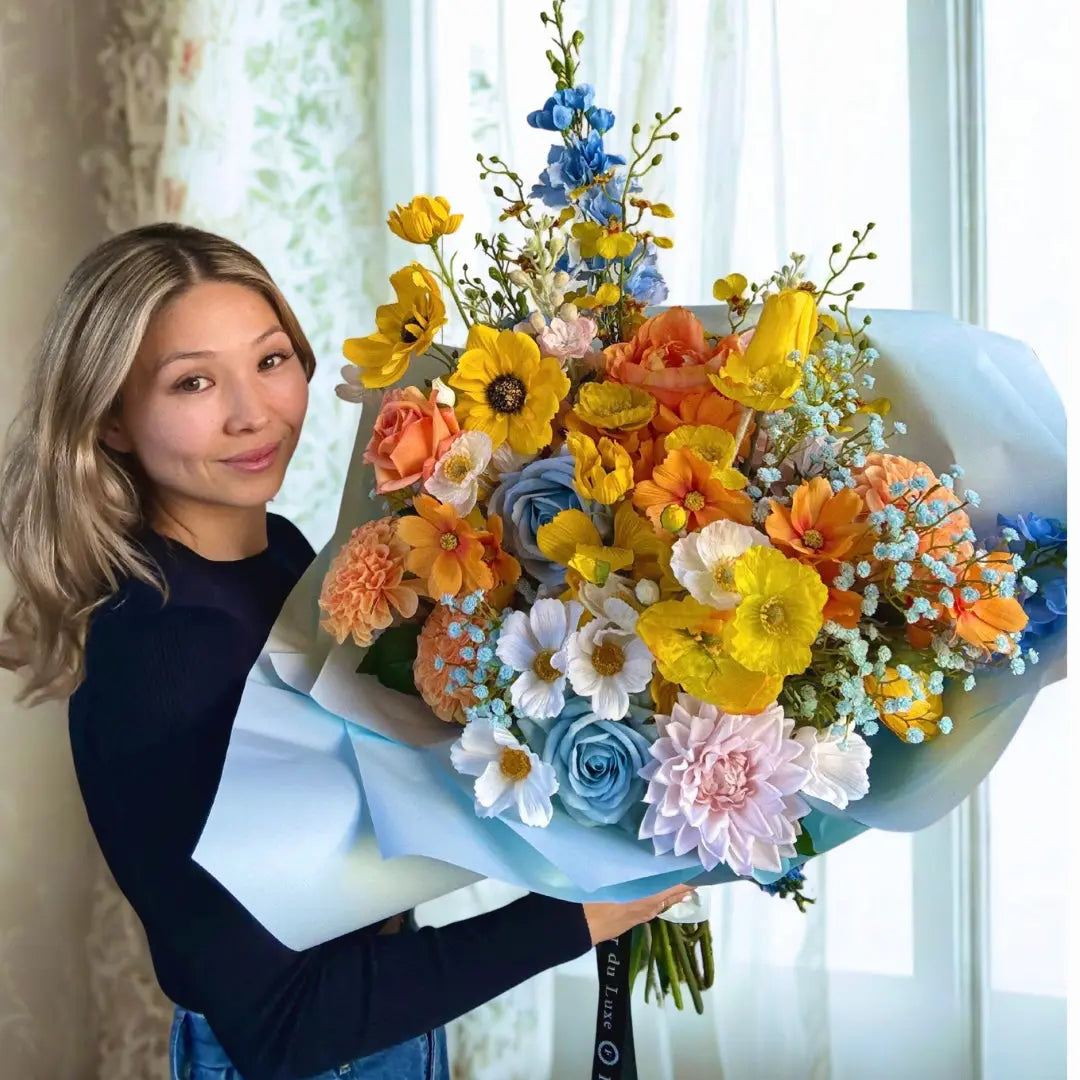 Woman holding a large bouquet of colorful flowers indoors.