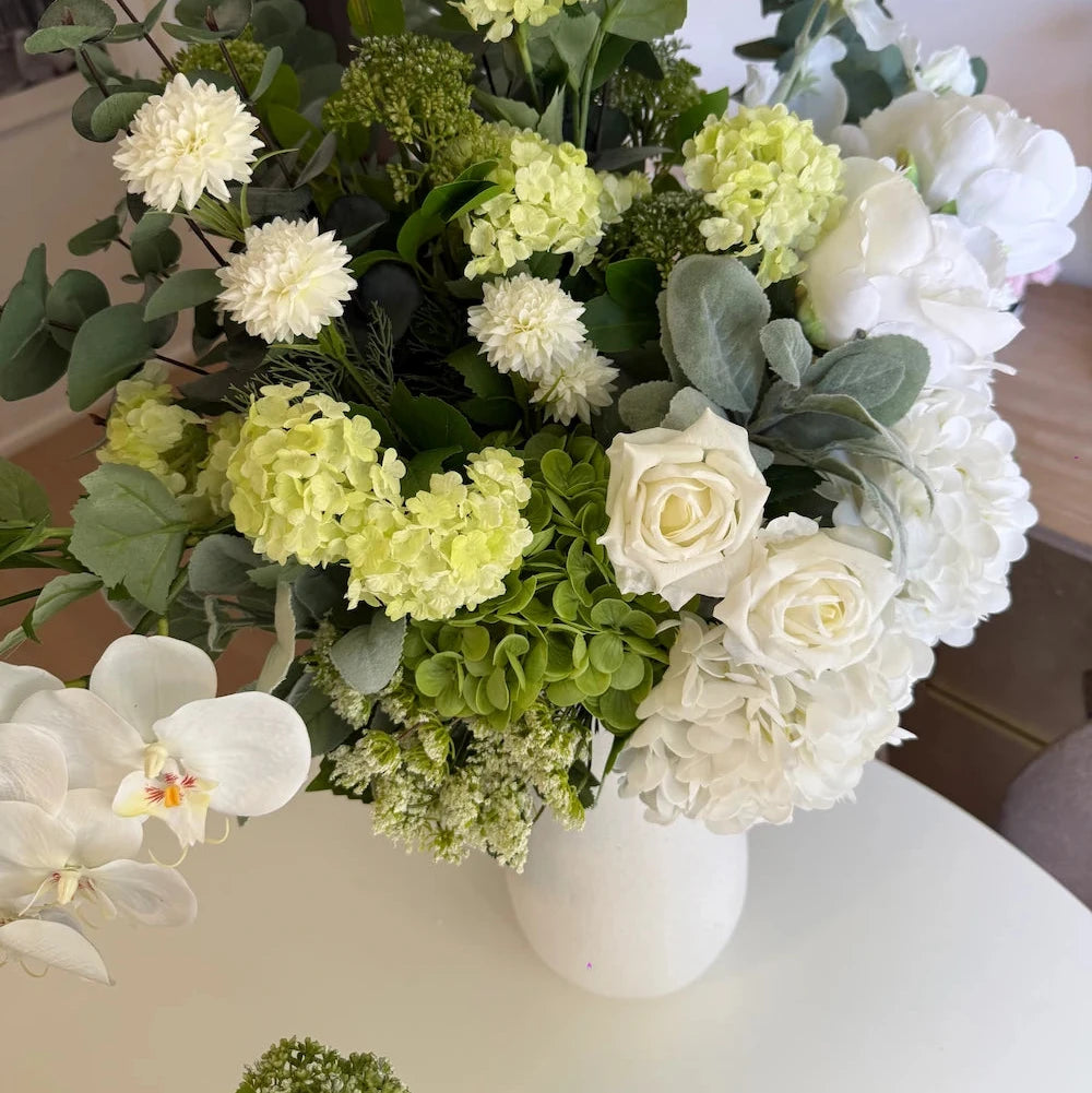 Bouquet of flowers with white and green colors in a vase on a table.