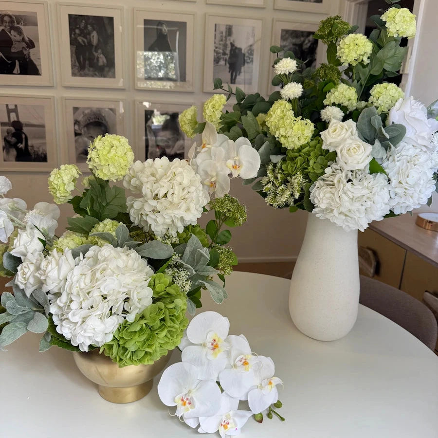 Floral arrangements on a table with a wall of black and white photos in the background