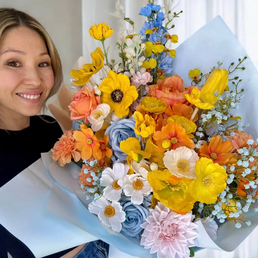 Woman holding a large bouquet of colorful flowers indoors.