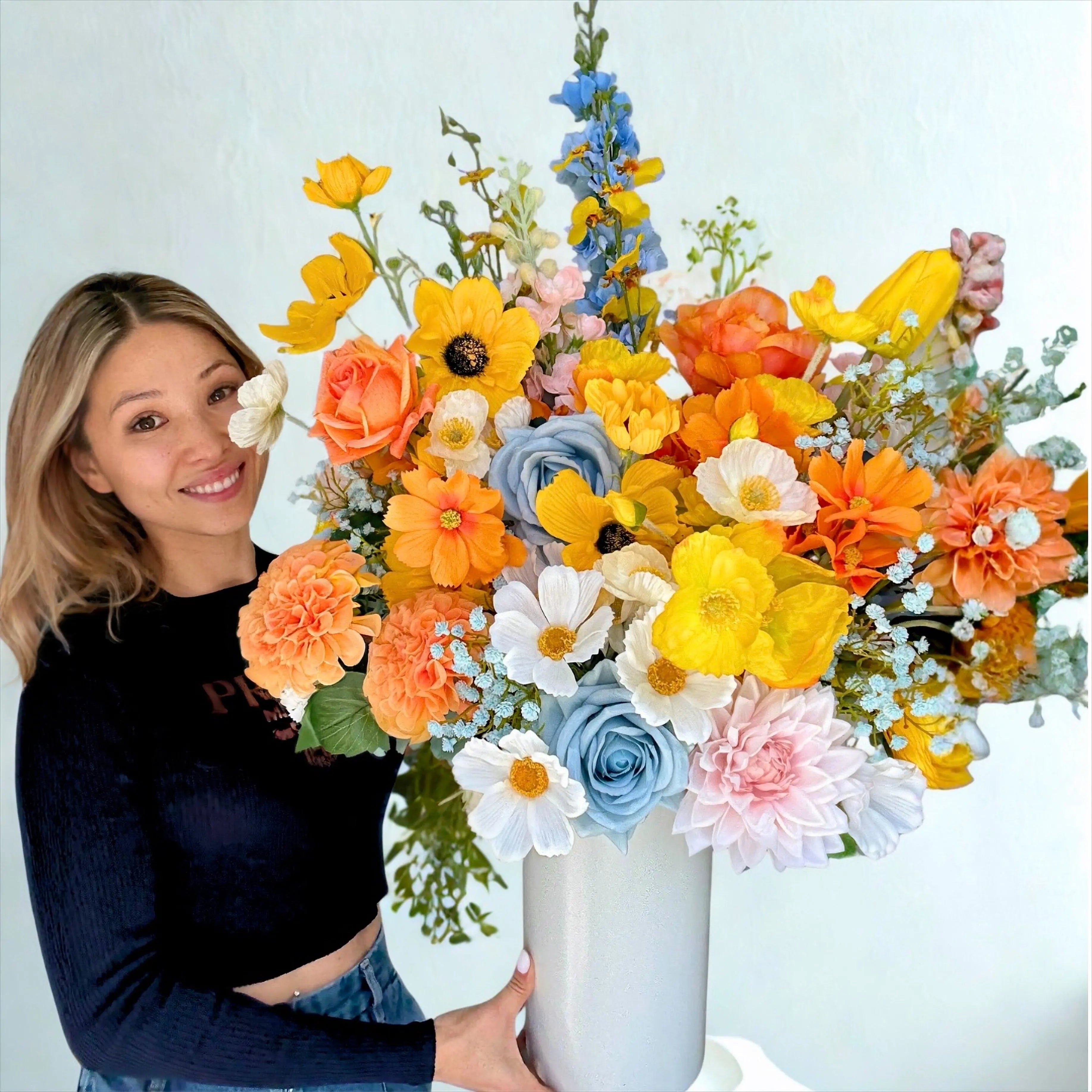 Woman holding a large, colorful bouquet of flowers against a light background