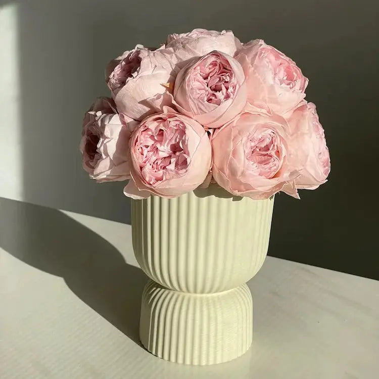 Light green ribbed vase with pink roses on a neutral background