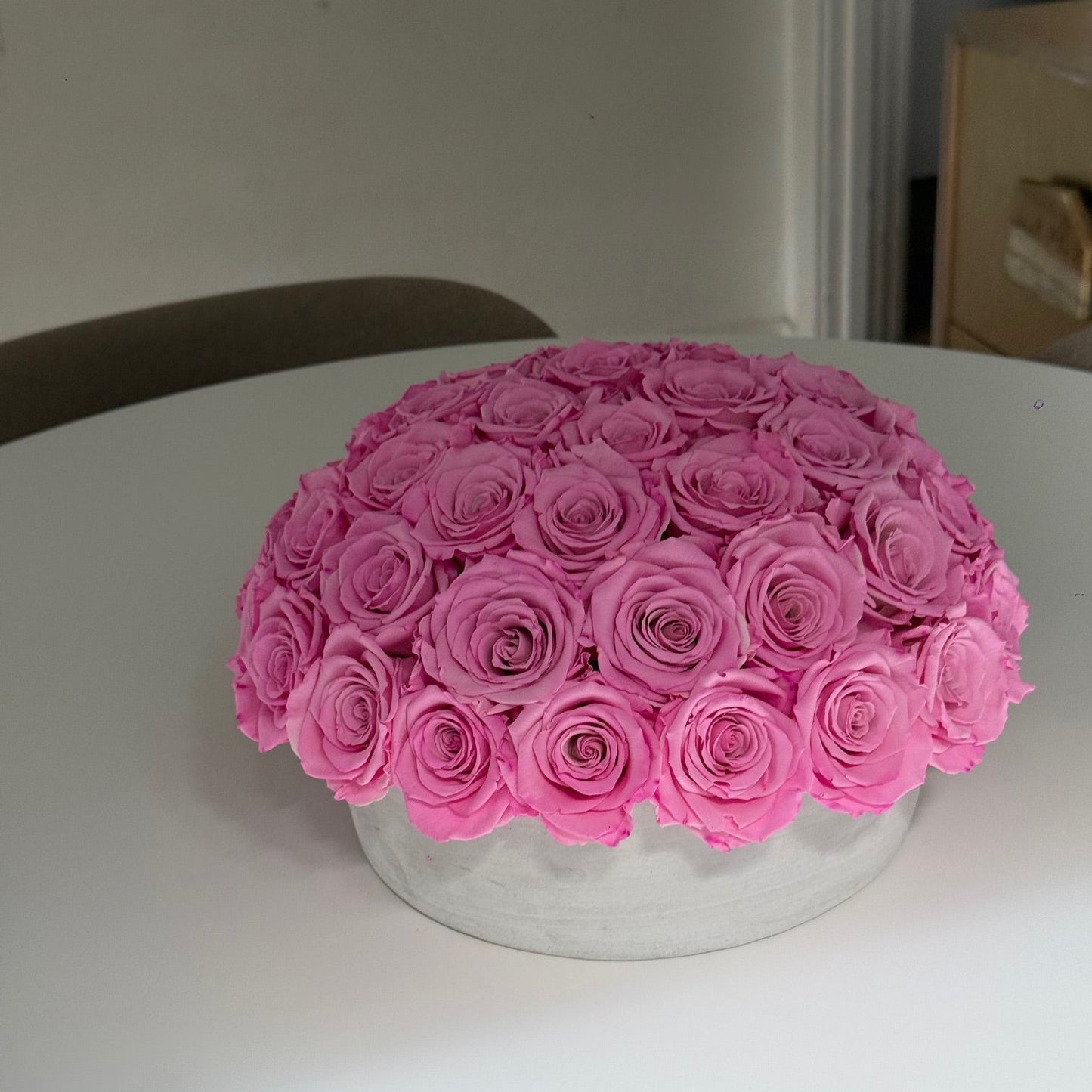 Side view of modern cement pot holding preserved Fleur du Luxe roses.