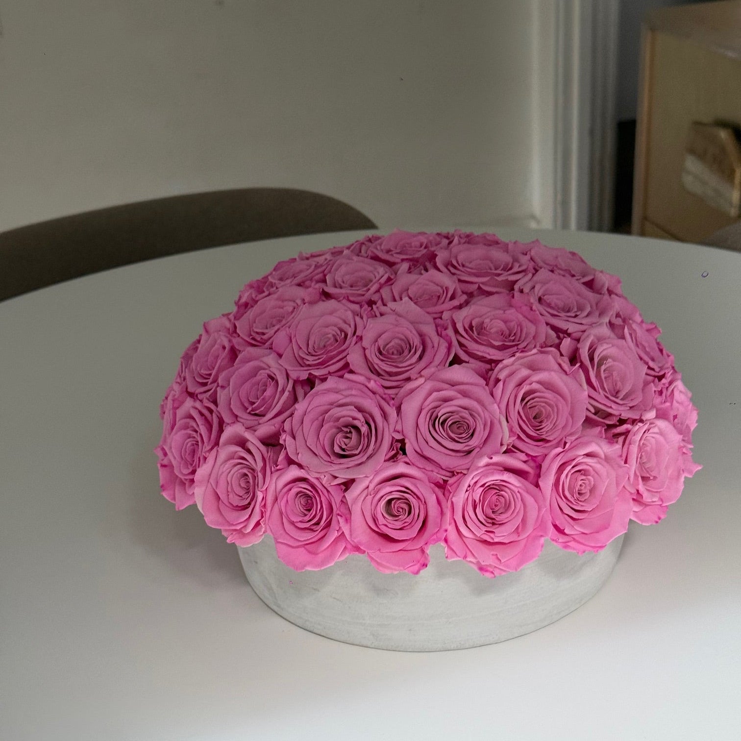 Side view of modern cement pot holding preserved Fleur du Luxe roses.