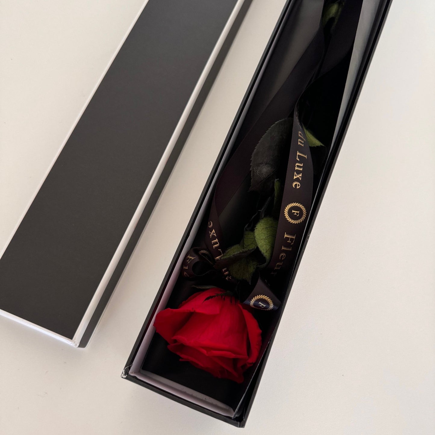 Single long-stemmed red rose elegantly presented in a luxurious gift box, preserved to last over a year.