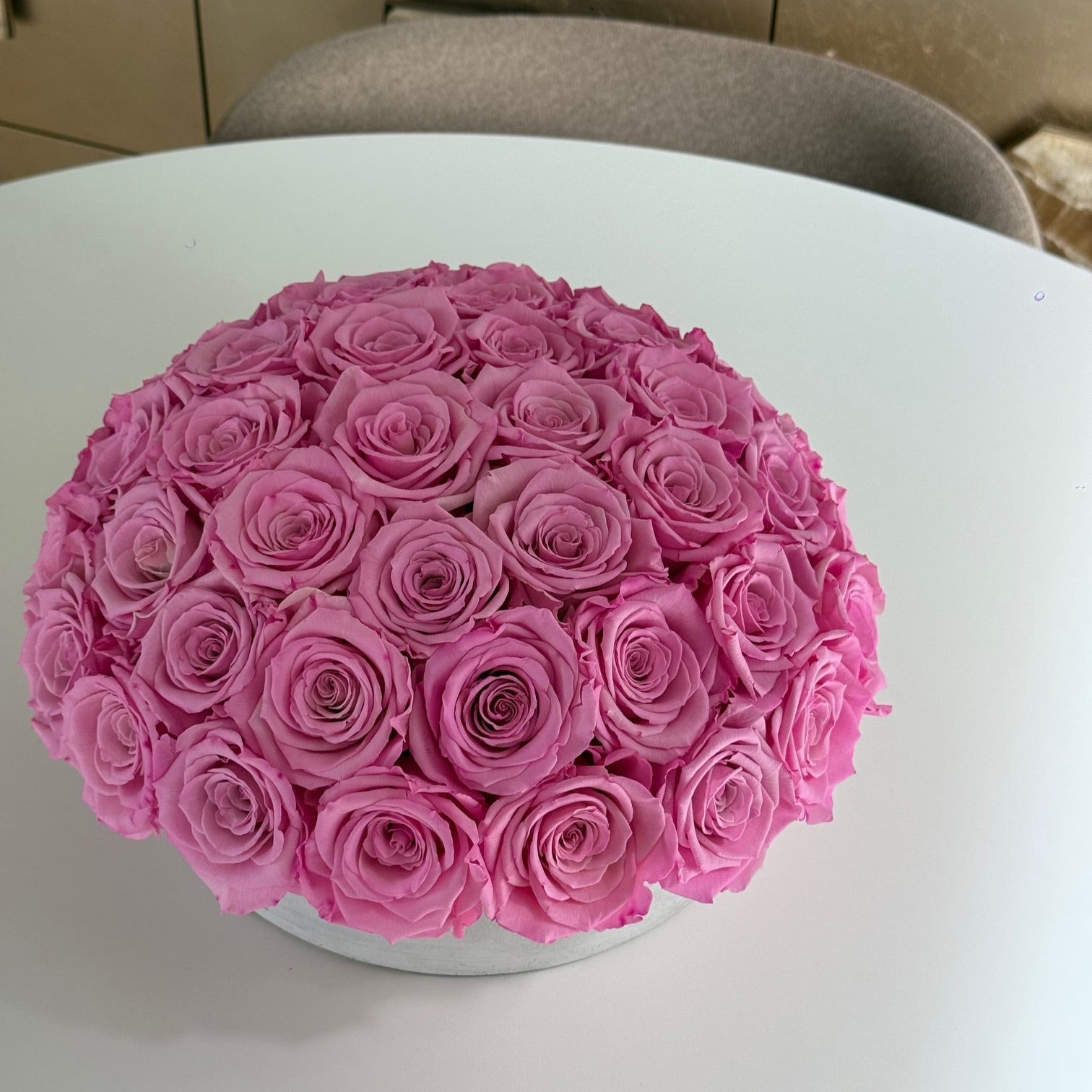 Top-down view of real preserved New York Pink roses arranged in cement pot.