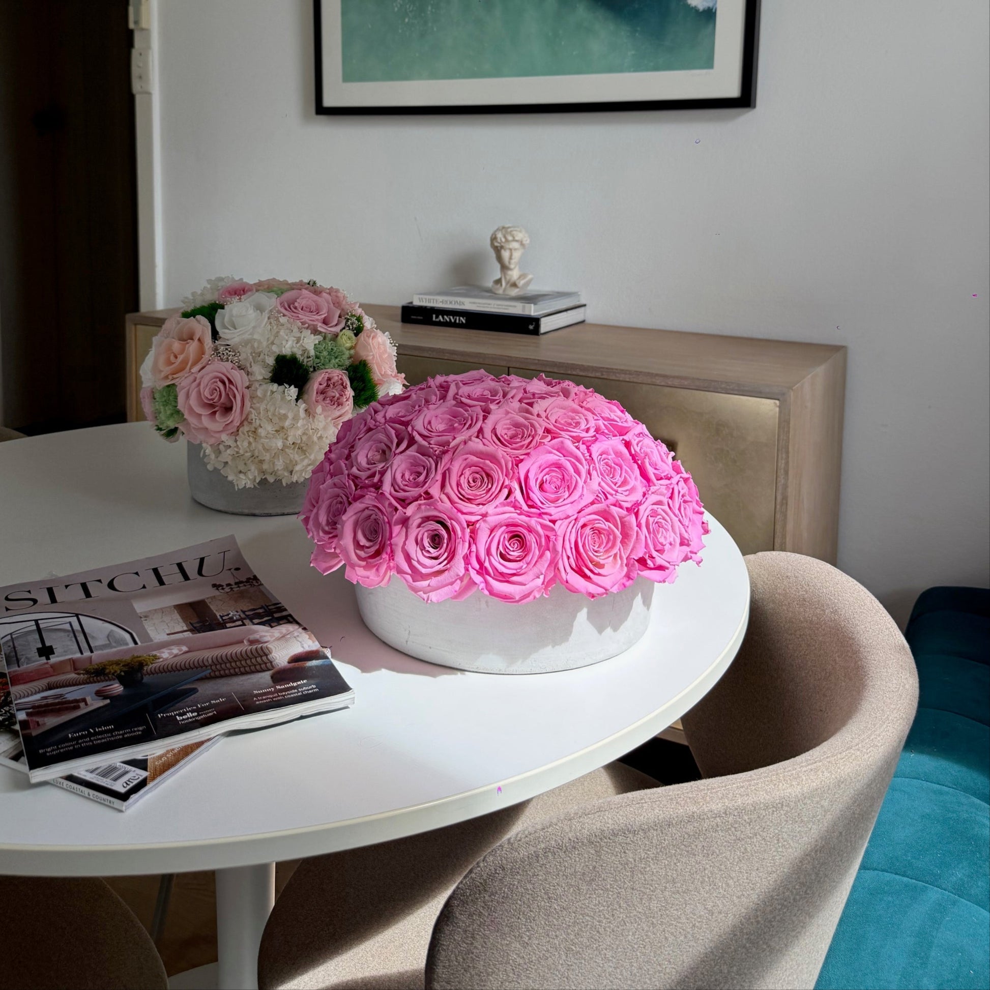 Dining table with Fleur du Luxe Cement Pot centerpiece featuring preserved pink roses.

