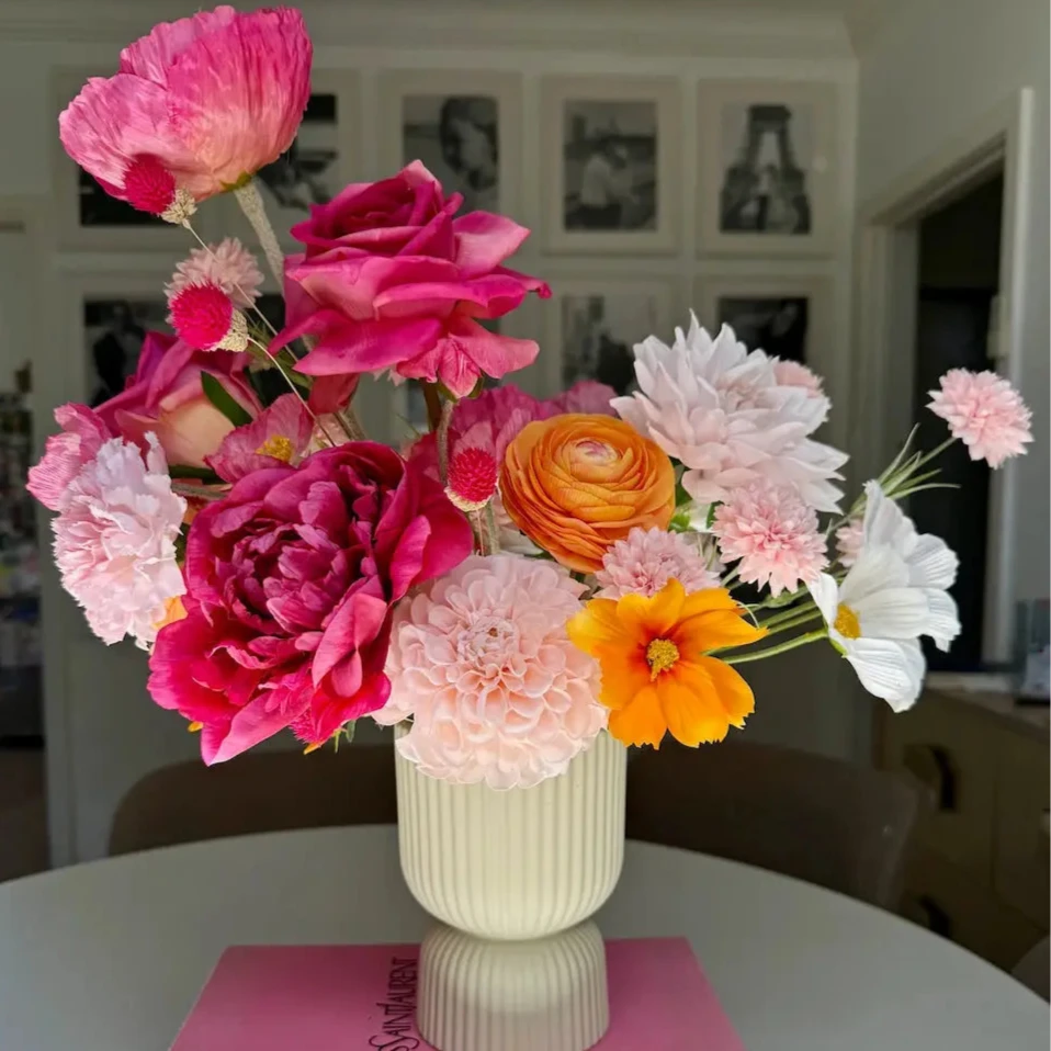 Colorful flower arrangement in a vase on top of two books with a blurred indoor background