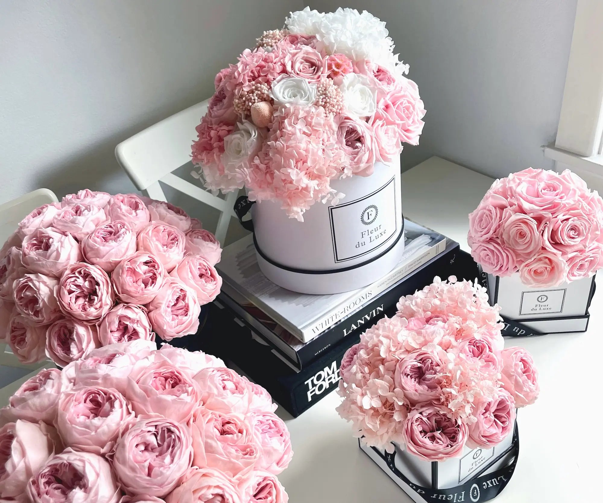 Pink and white flowers in a decorative box on a white surface with books.