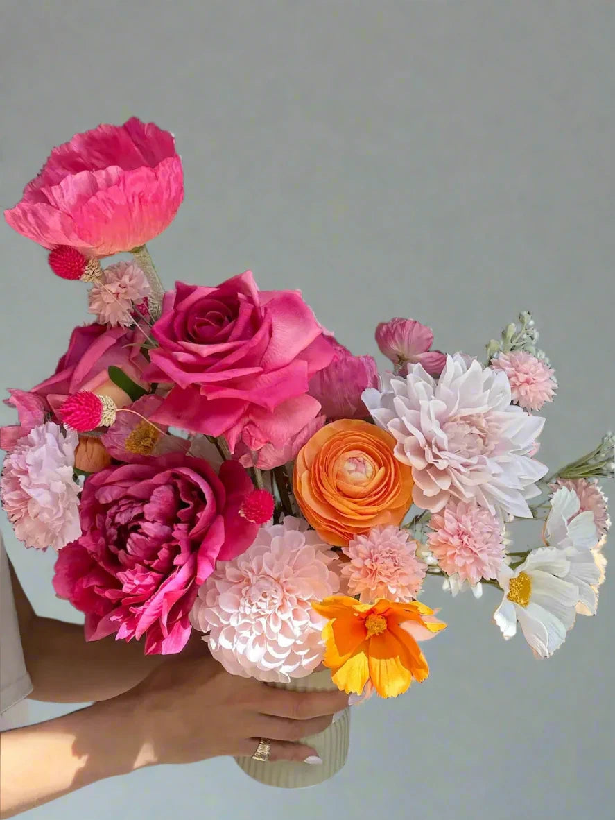 Bouquet of colorful flowers held by a person with a Louis Vuitton box in the background.