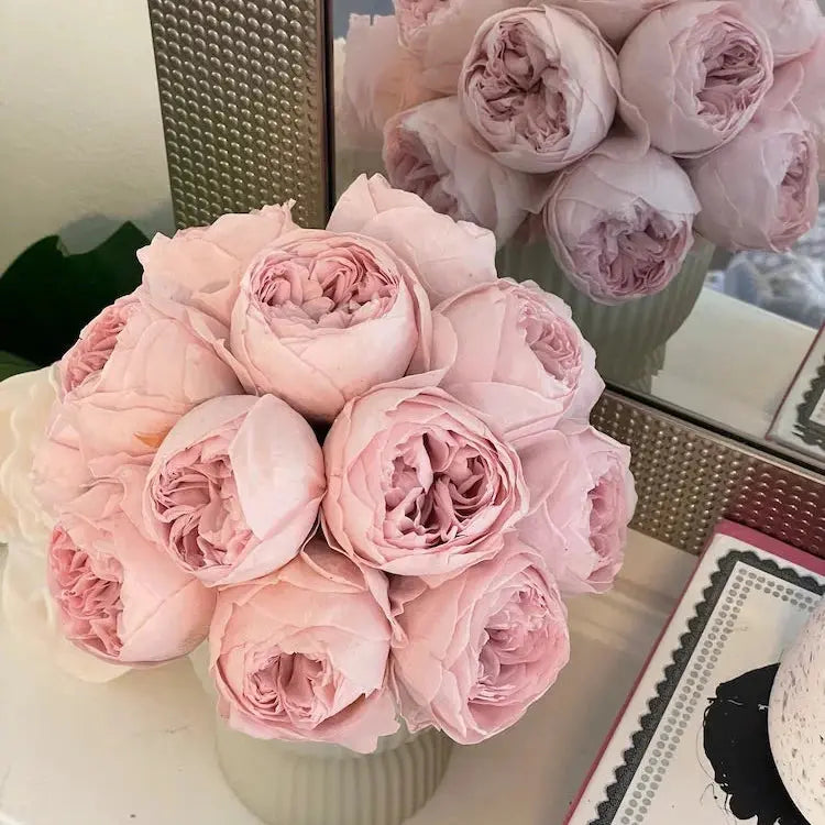 Bouquet of pink roses in a white vase on a table with a blurred background